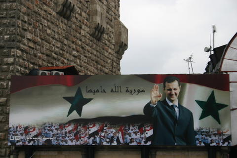 Billboard with portrait of Assad and the text Allah protects Syria on the old city wall of Damascus 2006 Photo: Bertil Videt, January 2006.